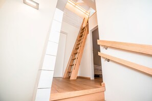 A narrow staircase with wooden steps and a wooden handrail, leading to a higher floor. - Vacation apartment 5 in Haus Freesenpark (Norderney)