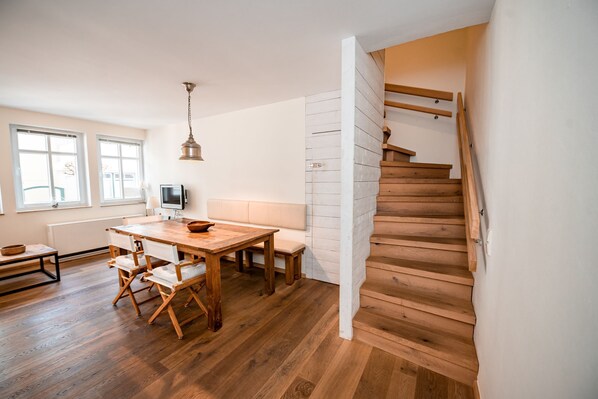 A modern kitchen with wooden flooring, a dining table, and a staircase. - Vacation apartment 5 in Haus Freesenpark (Norderney)