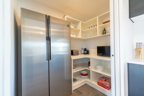 Eine kompakte Küche mit einem Edelstahlkühlschrank, weißen Regalen und einer Mikrowelle.