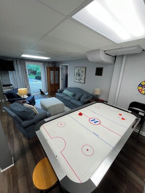 A room with a pool table, a sofa, a television, and a door leading to a garden.
