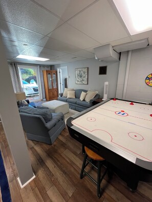 A room with a pool table, a sofa, and a door leading to a garage.