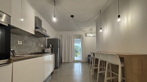 A modern kitchen with white cabinets, a built-in stove, and pendant lighting. - Levante Apartment - Style and Elegance 300 meters from the sea (Santa Margherita di Pula)