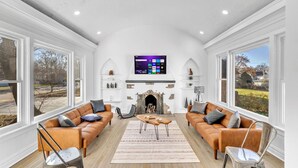 A spacious living room with two leather sofas, a fireplace, and a large TV mounted on the wall. - Comfortable SFH for Families & Groups • Easy Walk to Local Shops and Eateries (Downers Grove)