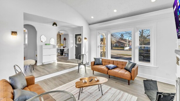 A spacious living room with a leather sofa, a coffee table, and a dining area with a white table and chairs. - Comfortable SFH for Families & Groups • Easy Walk to Local Shops and Eateries (Downers Grove)