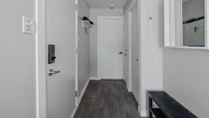 A narrow hallway with a wooden floor, white walls, and a door at the end. - Condo MSA - Ski Beaupré (Beauprã©)