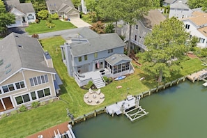 A residential property with a dock, a covered outdoor seating area, and a well-maintained lawn. - Water's Edge Retreat OCMD (Ocean Pines)