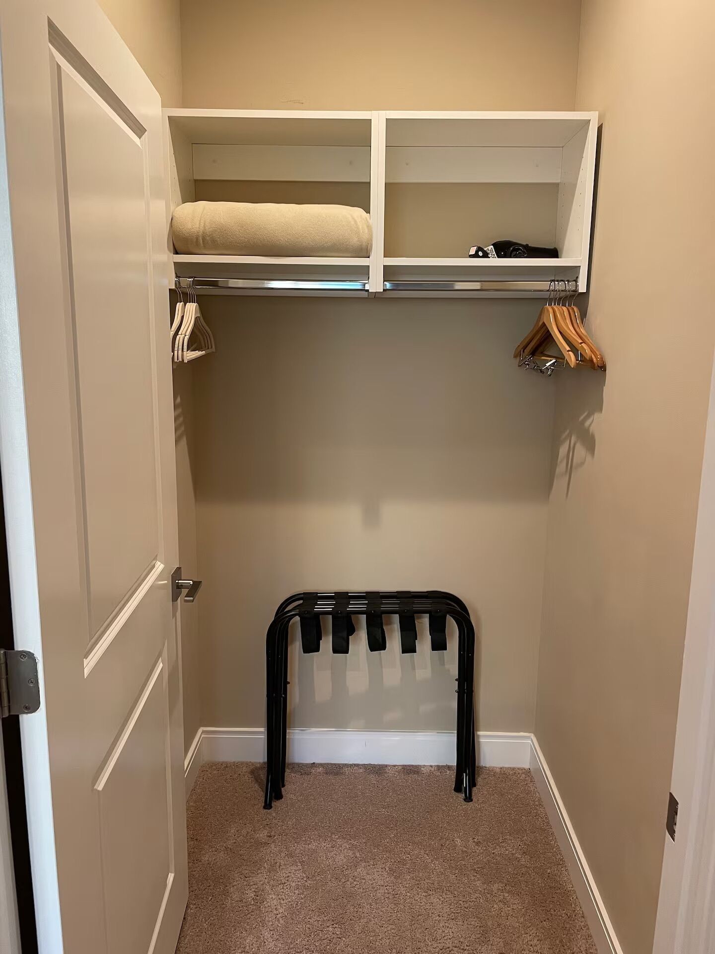 A walk-in closet with a hanging rack, shelves, and a door.