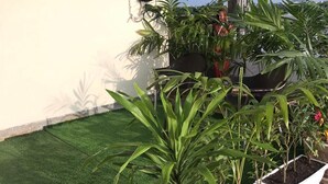Een dakbostuin met verschillende plantenpotten en een klein waterpartij.