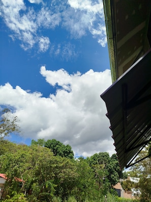 Une vue d’un bâtiment doté d’un toit en pente, avec un ciel bleu clair parsemé de nuages.
