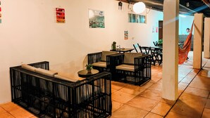 Ein Restaurant mit Außenbereich, darunter schwarze Korbstühle und ein Tisch mit einem Laptop.