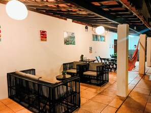 Un restaurante con mesas al aire libre, incluyendo sillas de mimbre negro y una mesa con una computadora portátil.