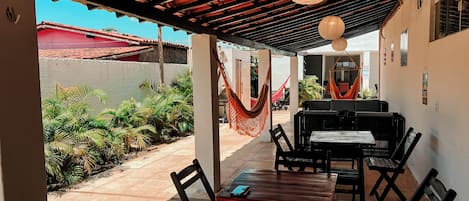 Una terrazza esterna con tavoli, sedie, un'amaca e piante in vaso.