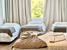 Quarto de hotel com três camas, cada uma com toalha e cobertor.