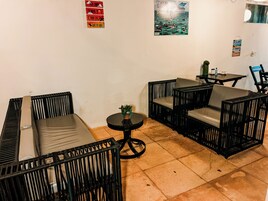 Quarto com sofá, duas poltronas, uma mesinha e um vaso de planta.