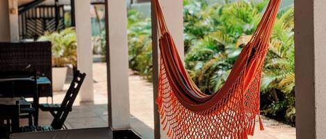 A hammock hanging between pillars in a covered outdoor area with a patio table and chairs.