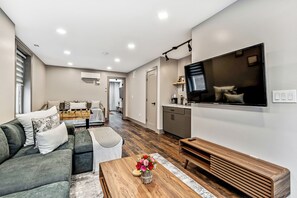 A modern living room with a sofa, coffee table, and a flat-screen TV mounted on the wall. - Designer 5Bed - 4Bath Home in Old City! A Plus Location (Philadelphia)