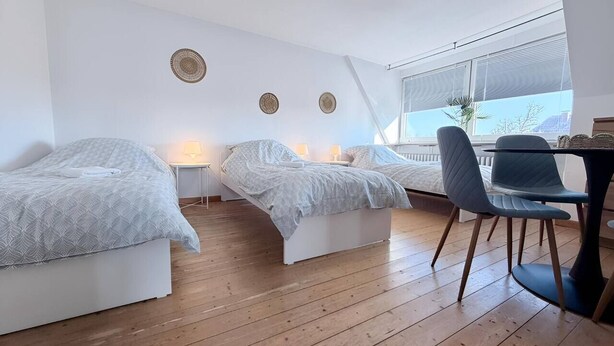 A modern bedroom with two single beds, a small table, and a chair. - sleepWELL-Nordhorn II – Neu & Modern zentrale Lage (Nordhorn)
