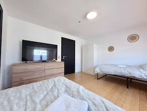 Ein modernes Schlafzimmer mit Fernseher, Kleiderschrank, Bett und Nachttisch.