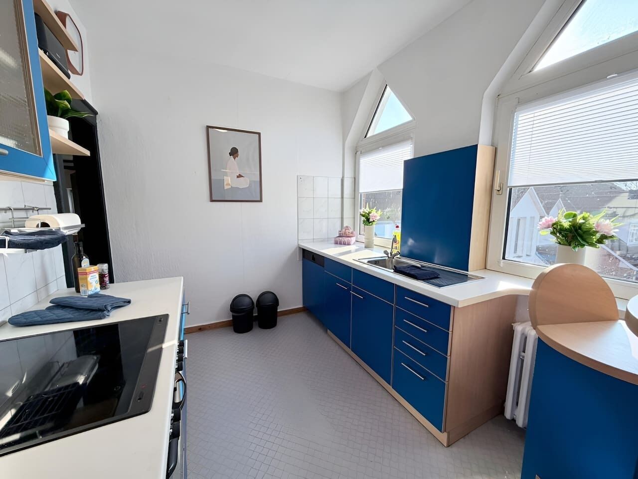 A modern kitchen with blue cabinets, a built-in oven, and a window with a view of the city.