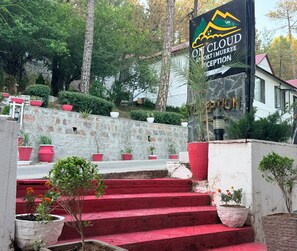 A reception area with a stone wall, red steps, and potted plants. - On Cloud Resort (Murree)