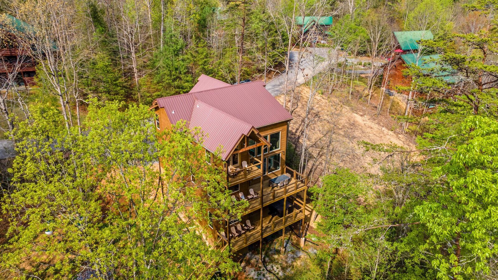 Une cabane en bois avec un toit rouge, entourée d’une forêt dense.