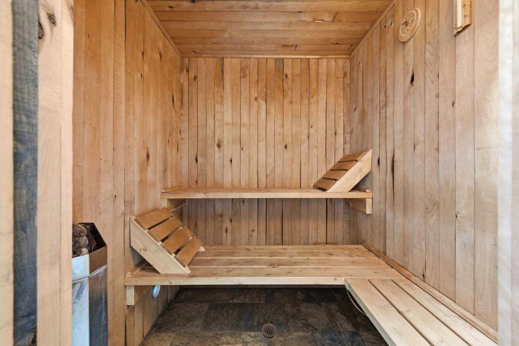 Un sauna en bois avec des bancs et un sol en pierre.
