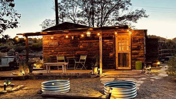 Una cabaña rústica con fachada de madera, un porche con asientos y un letrero que dice "CABIN".