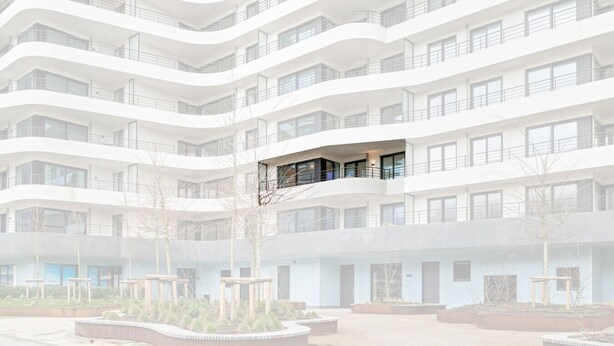 Un edificio a più piani con balconi, un cortile centrale e un design architettonico moderno.