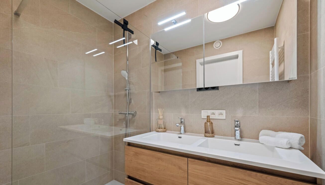 A modern bathroom with a glass-enclosed shower, a double sink vanity, and a mirror above the sink.