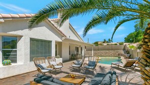 Une terrasse avec des meubles d’extérieur, une piscine et un bâtiment blanc doté d’un mur en pierre.