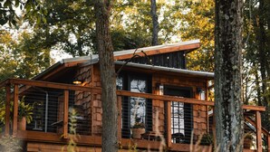 A wooden cabin with a balcony, surrounded by trees. - Lux Cabin on Farm, River, Animals, Projector (Montgomery)