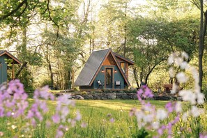 Una cabaña con techo inclinado, base de piedra y terraza de madera.