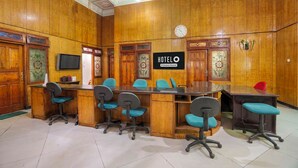 A hotel conference room with a wooden interior, a reception desk, and a clock on the wall. - OYO 95170 Purnama Baru Syariah (Selorejo)