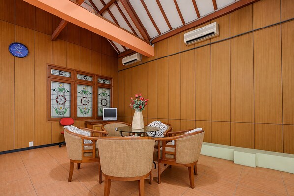 Ein Zimmer mit holzgetäfelten Wänden, einem runden Tisch mit Stühlen, einer Uhr und einem Fernseher.
