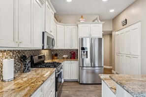 A kitchen with white cabinets, a stainless steel refrigerator, a microwave, and a gas stove. - Hidden Oasis Intimate 3 BR Home/ Private Pool/ Jacuzzi/ Fire Pit/ Glendale (Glendale)