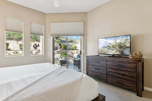 A bedroom with a large bed, a TV on a wooden dresser, and a sliding glass door leading to an outdoor patio. - Hidden Oasis Intimate 3 BR Home/ Private Pool/ Jacuzzi/ Fire Pit/ Glendale (Glendale)