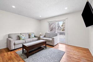 A living room with a gray sofa, a wooden coffee table, and a gray rug. - Budget Friendly 3BR YYC Airport Access With Free Parking & Wifi (Calgary)