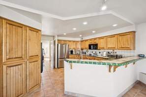 A spacious kitchen with wooden cabinets, a central island, stainless steel appliances, and a tiled backsplash. - Scottsdale Oasis with Pool & Mountain Views (Scottsdale)