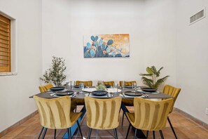 A dining area with a table set for six, yellow chairs, and a cactus-themed painting on the wall. - Scottsdale Oasis with Pool & Mountain Views (Scottsdale)