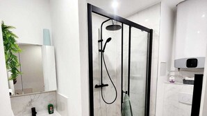 A modern bathroom with a glass-enclosed shower, a white sink with a marble countertop, and a toilet. - Apparttement distrito10 (Paris)