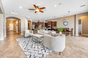 A spacious living room with a large sofa, a coffee table, and a patterned rug. - South Mountain-view home with private pool & Ping-Pong - near hiking trails (Phoenix)
