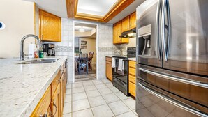 Una cucina moderna con mobili in legno, elettrodomestici in acciaio inossidabile e un piano di lavoro in marmo.