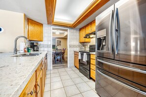 A modern kitchen with wooden cabinets, stainless steel appliances, and a marble countertop. - Quiet Scottsdale retreat with enclosed yard, pool, patio, grill, game room & W/D (Scottsdale)