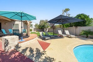 A backyard with a swimming pool, lounge chairs, and umbrellas. - Quiet Scottsdale retreat with enclosed yard, pool, patio, grill, game room & W/D (Scottsdale)