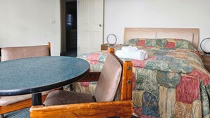 Ein Hotelzimmer mit einem Bett, einem runden Tisch, zwei Stühlen und einer Tür zu einem Flur.