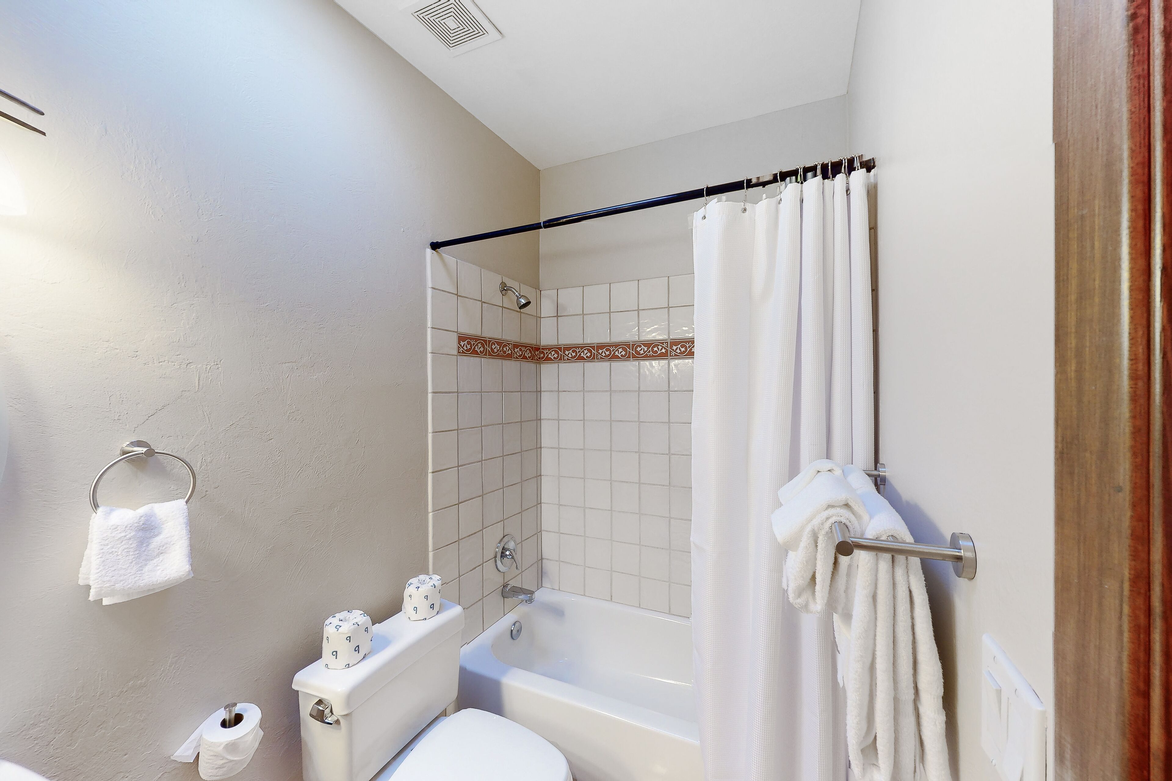 Un baño con bañera, inodoro, cortina de ducha y toallas.