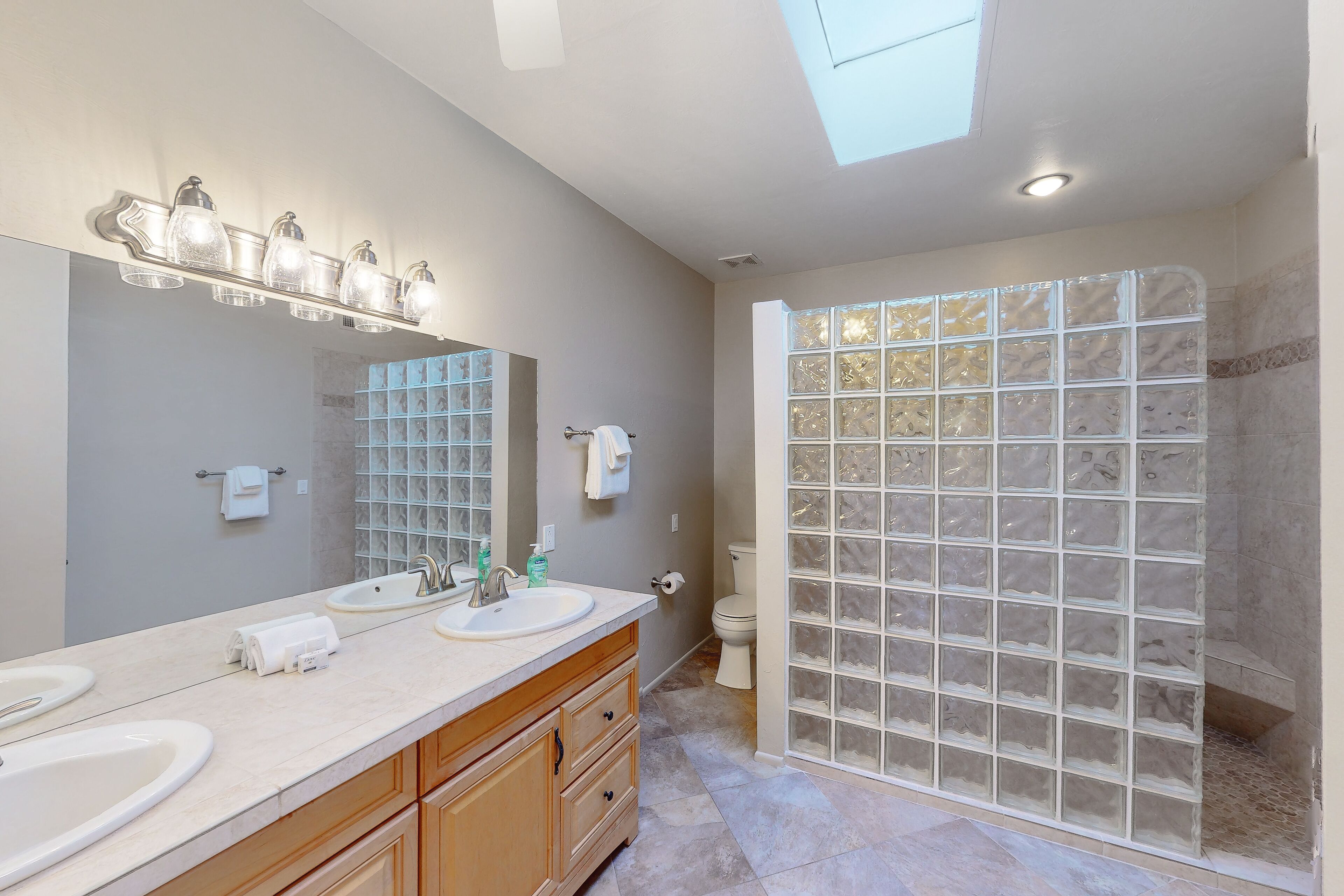 A bathroom with two sinks, a large mirror, and a glass shower enclosure.