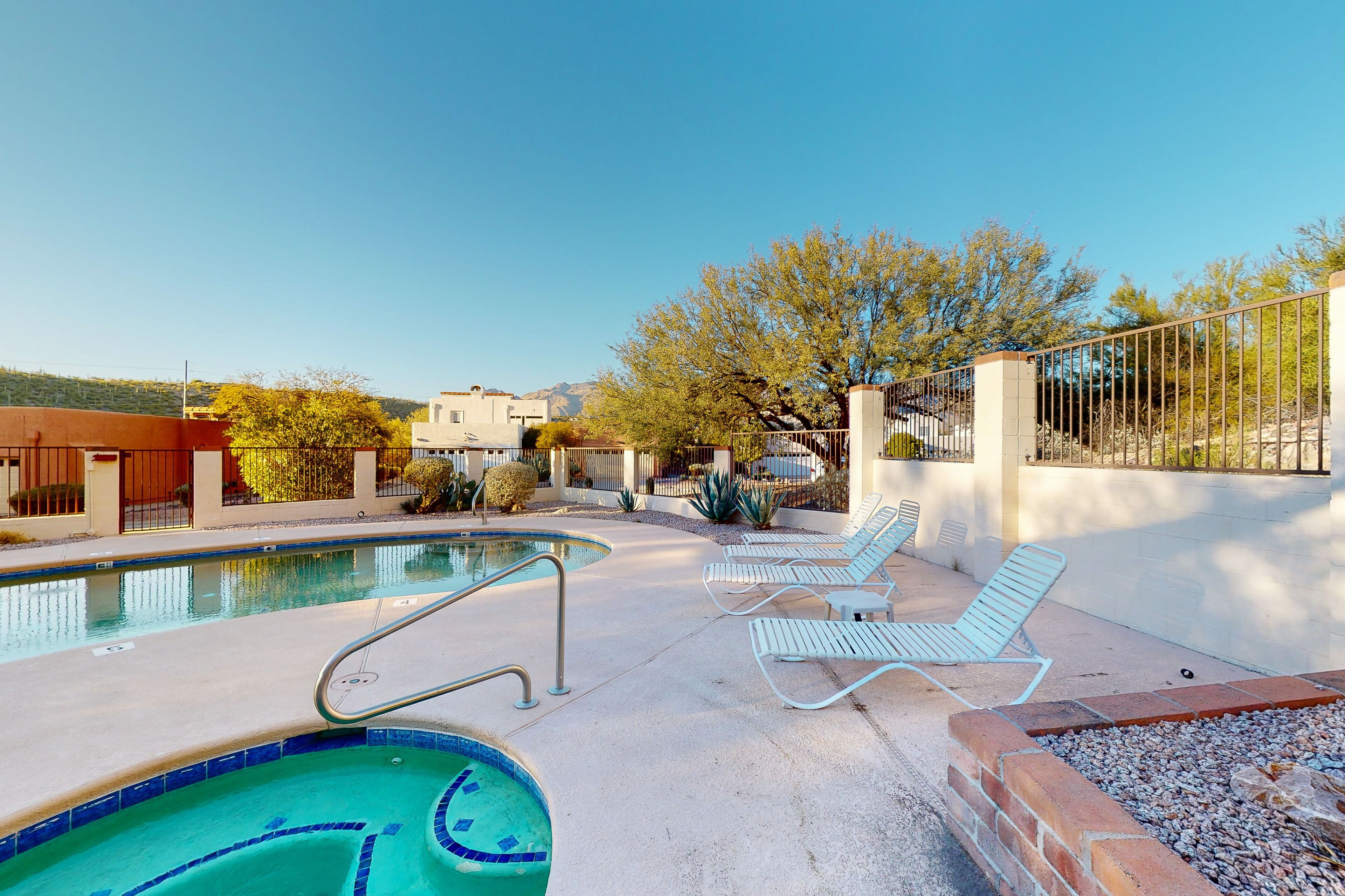 A swimming pool with lounge chairs and a view of the surrounding area.