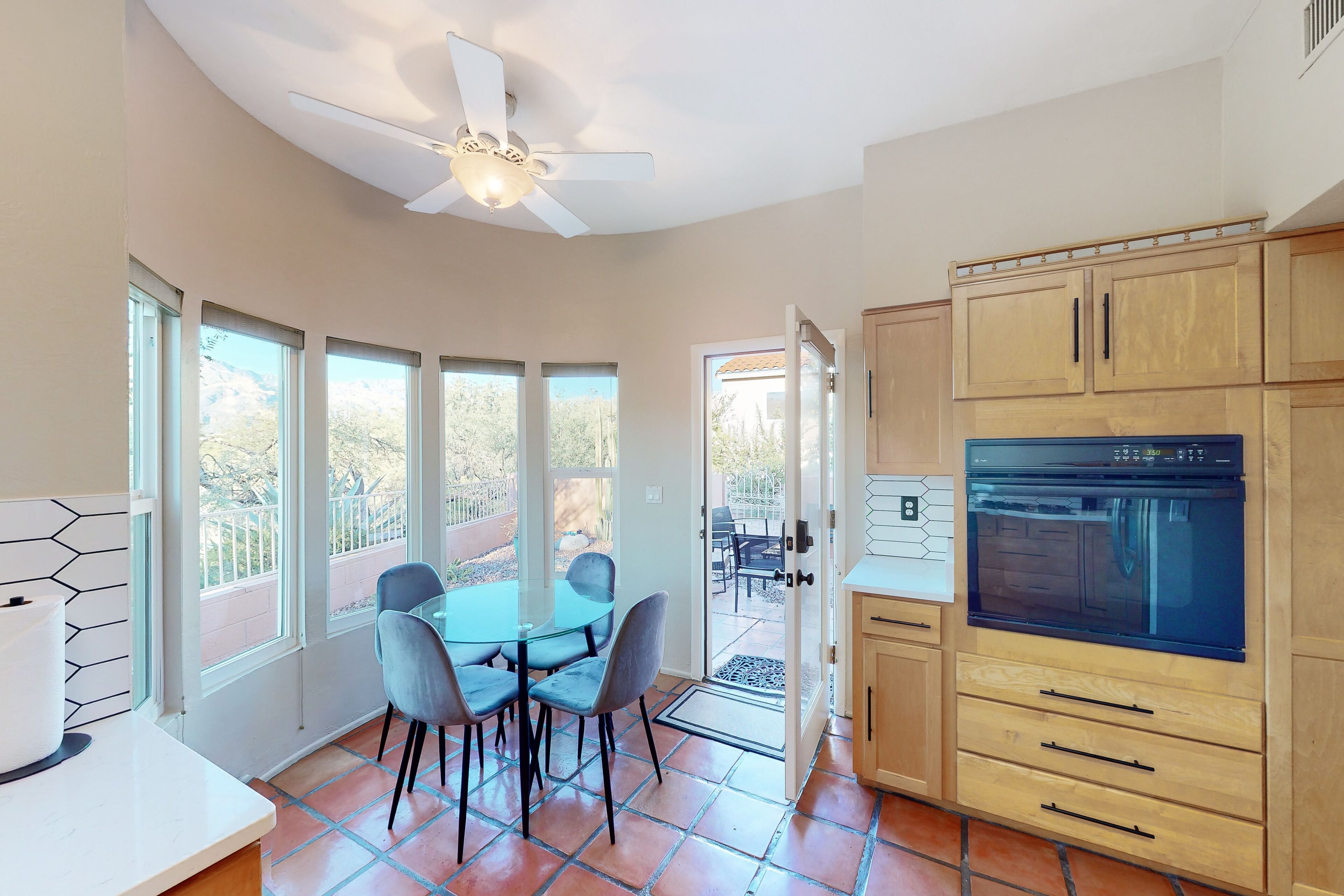 A kitchen with a built-in oven, wooden cabinets, and a dining area with a table and chairs.