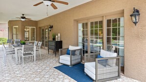 An outdoor patio with a dining table, chairs, wicker furniture, ceiling fans, and a patterned floor. - Beautiful single-level home with enclosed yard, pool, patio & WiFi (Scottsdale)